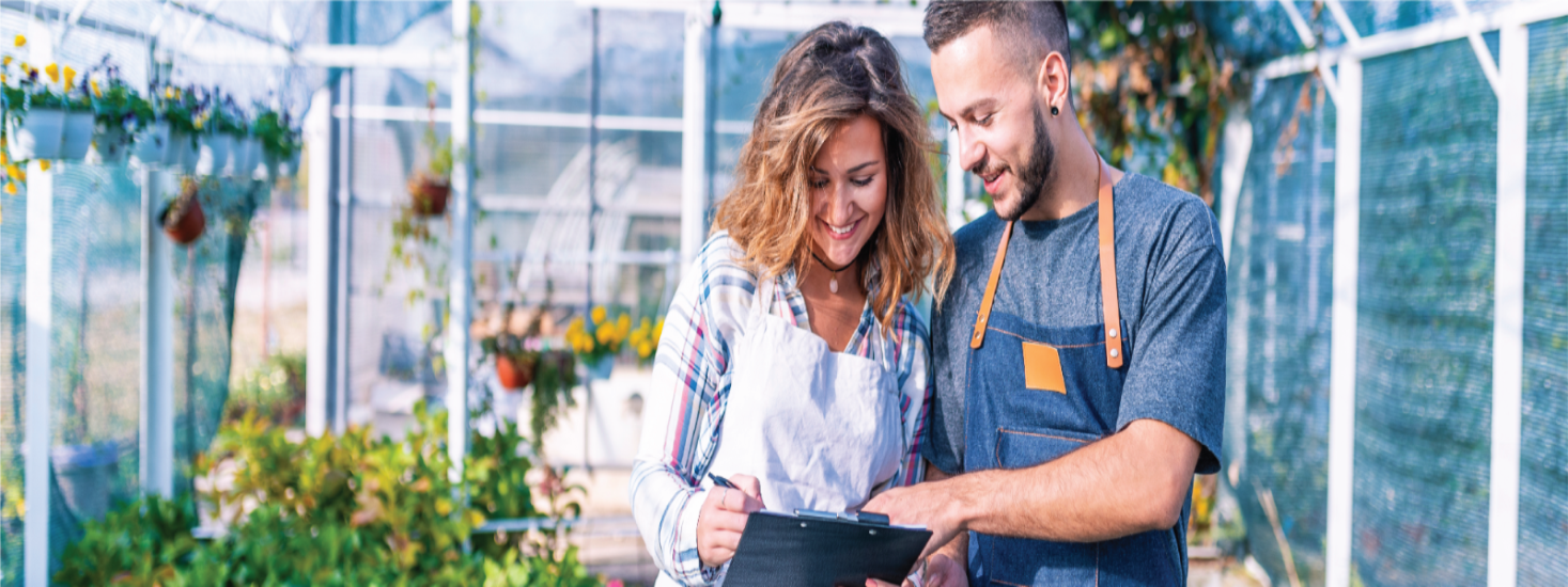 man and woman in greenhouse looking at chart
